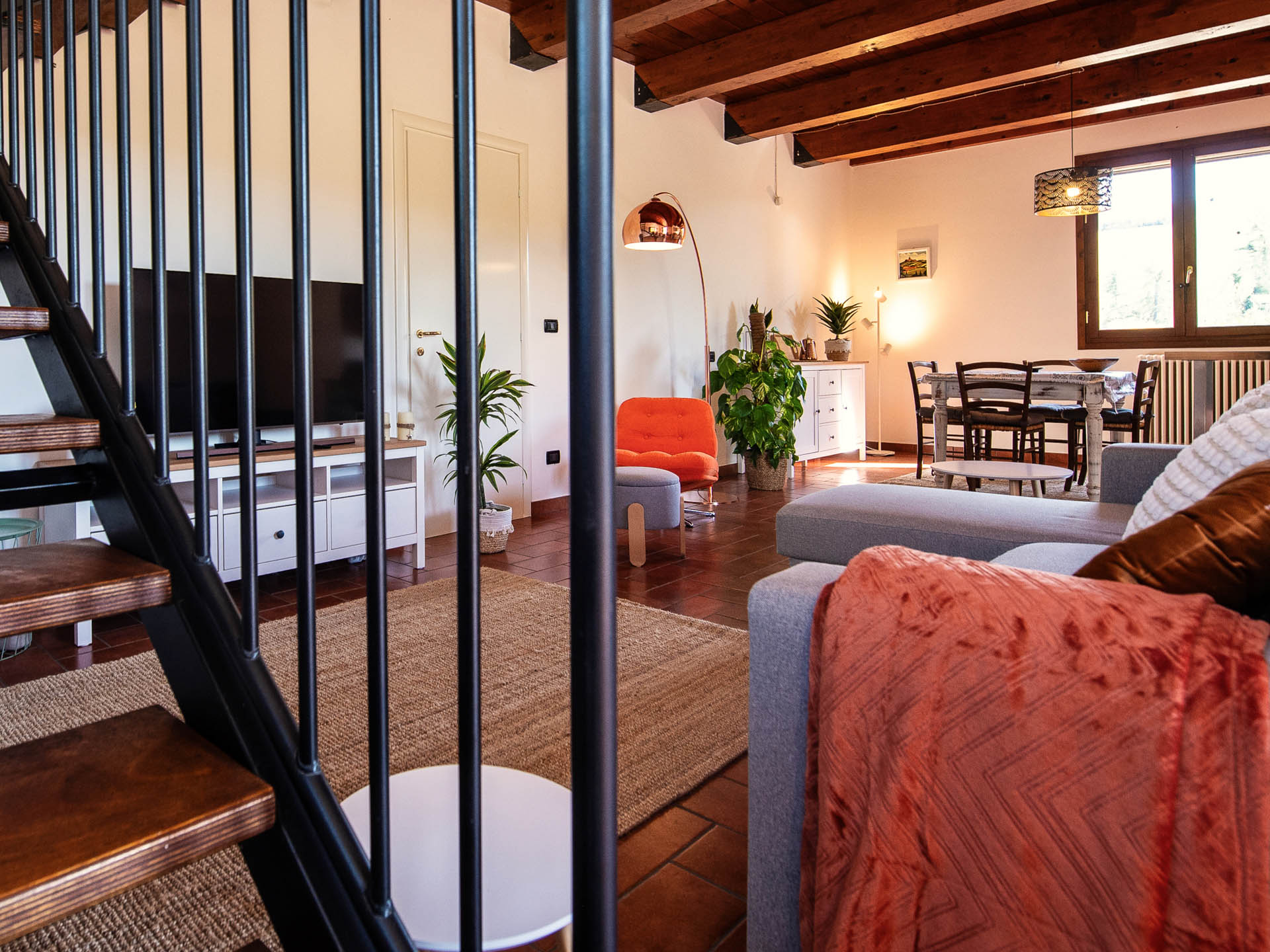 Living room with staircase, orange armchair and grey sofa